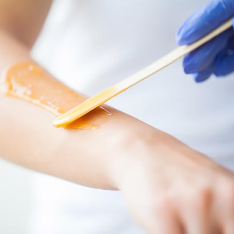 waxing specialist applying wax to arm
